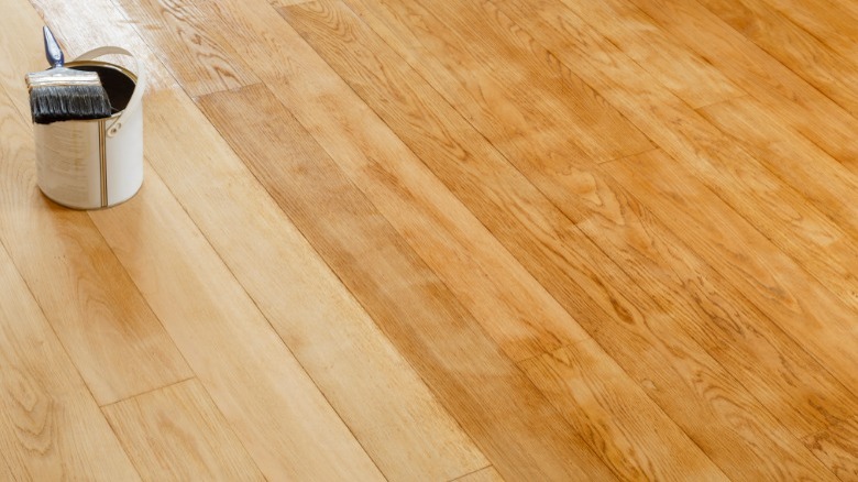 Half-stained wood floor with bucket/paintbrush