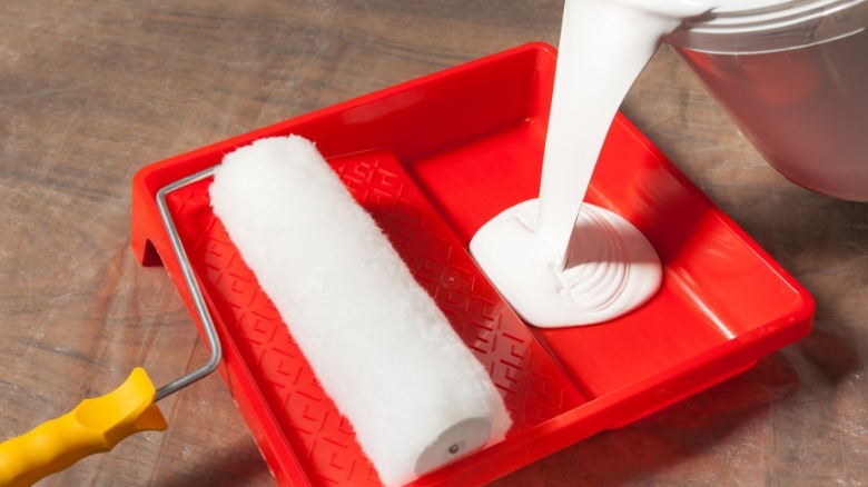 Pouring white paint into red tray