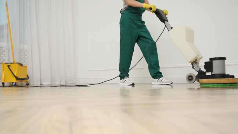 Person in green coveralls using floor buffing machine