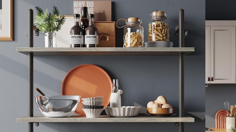 Floating shelves with food and dishes in the kitchen against gray wall