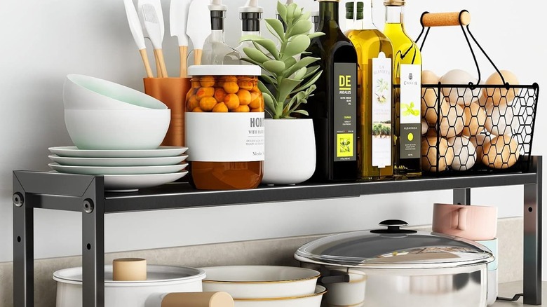 An expandable shelf with dishes and pantry items on the kitchen counter