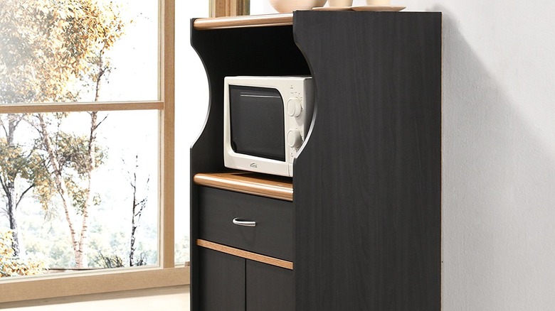 A black and brown microwave cart with cabinets