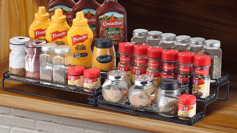 A tiered organizer with spices in a cabinet