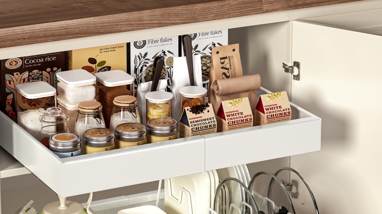 A pull out shelf with food and cookware in a cabinet