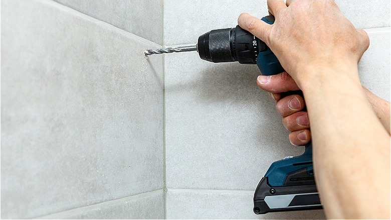 Hands drilling into tile wall