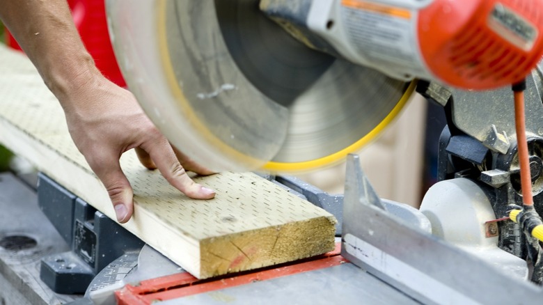 Person using a miter saw to cut a piece of lumber