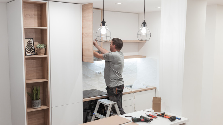 Man installing kitchen cabinet 