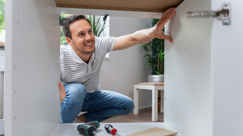 Man looking inside cabinet