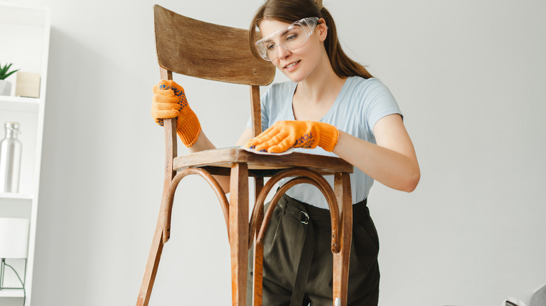 woman polishing wooden chair