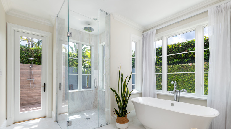 A modern coastal bathroom with a window and sheer curtains