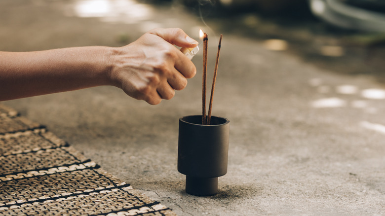 person lighting incense sticks outside