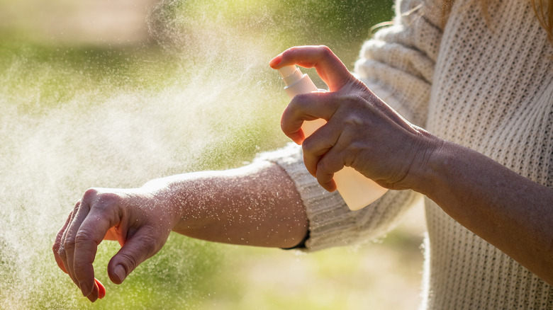 a person spraying mosquito repellent