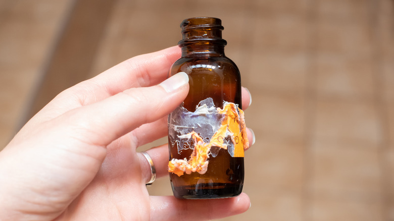 Person holding amber bottle with partially removed label