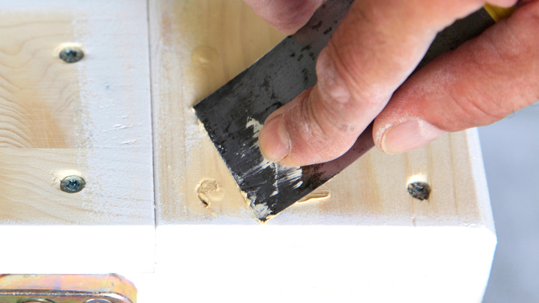 Wood filler applied to the top hole in a wood plank