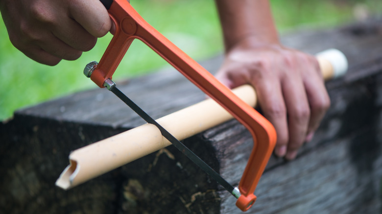 a hacksaw cutting a pipe