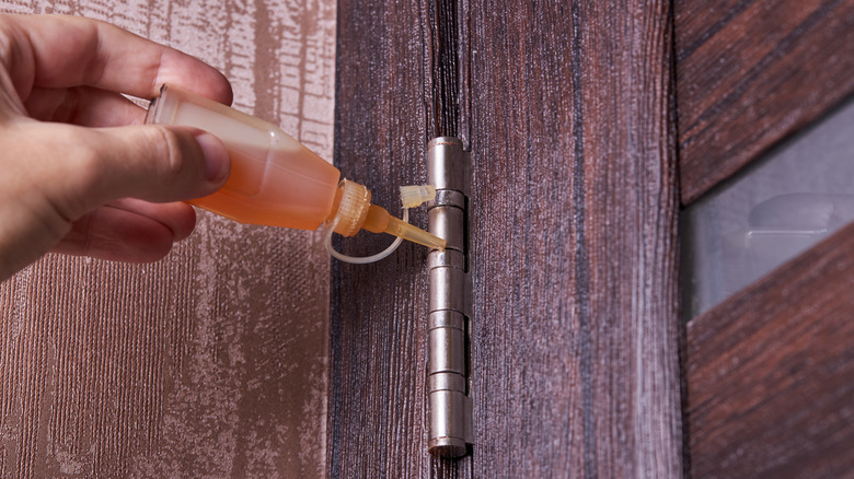 Person applying a lubricant to the outside of a door hinge