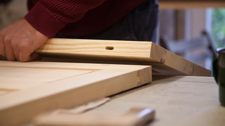 A man's hands building cabinets out of raw wood