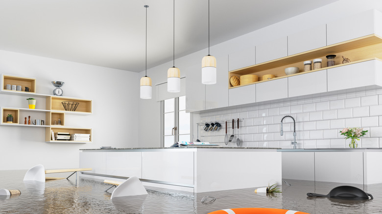 A modern, white kitchen that is severely flooded