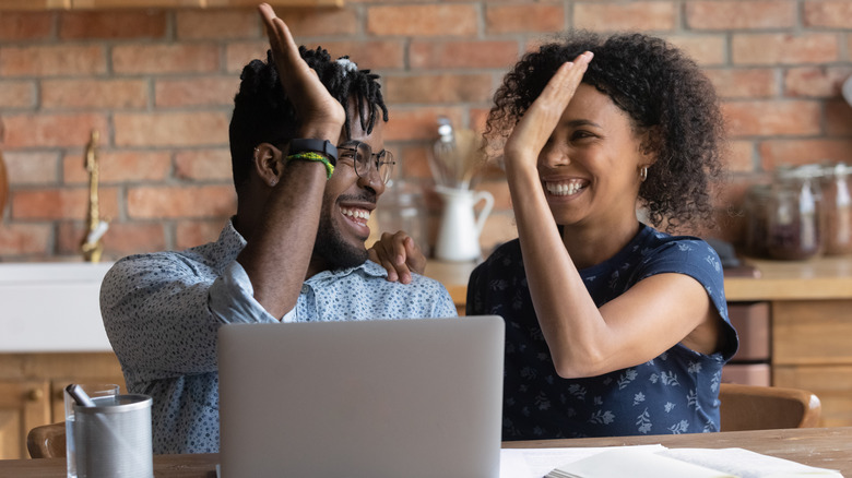 Couple high-fiving with laptop