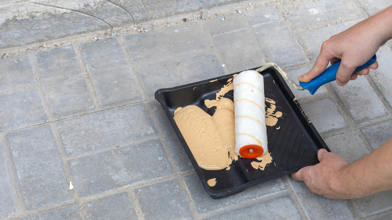 Person painting brick flooring with roller