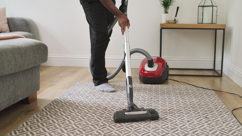 Man vacuuming area rug