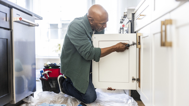 A handyman replaces kitchen cabinets.