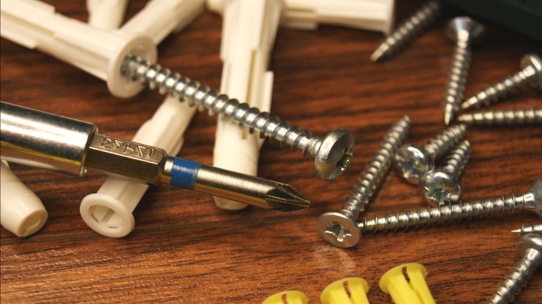 Screwdriver with plastic expansion anchors and screws on wood surface