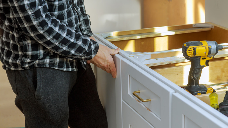 Person assembling cabinet with tool