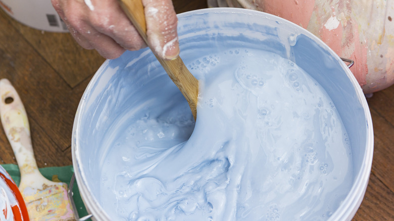 Man stirring light blue paint