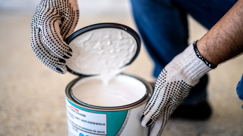 Construction worker opening paint can