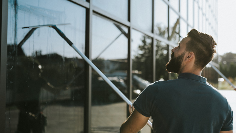 man washing windows with squeegee