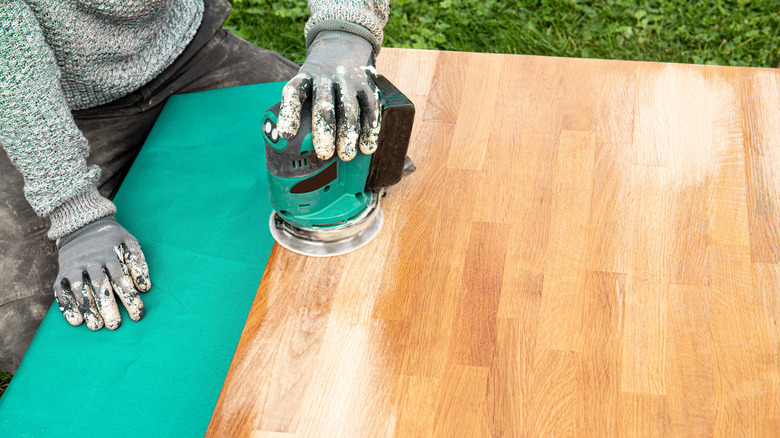 A person's hands sanding a butcher block counter before install