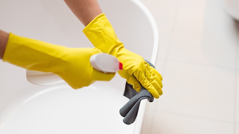 Woman using spray bottle on bathtub