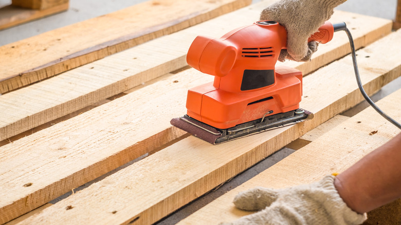 Person sanding a wood pallet 