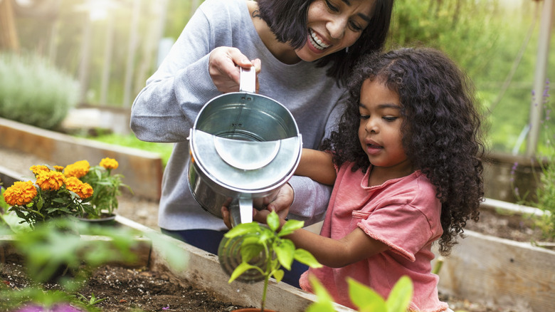 Woman watering plants with child