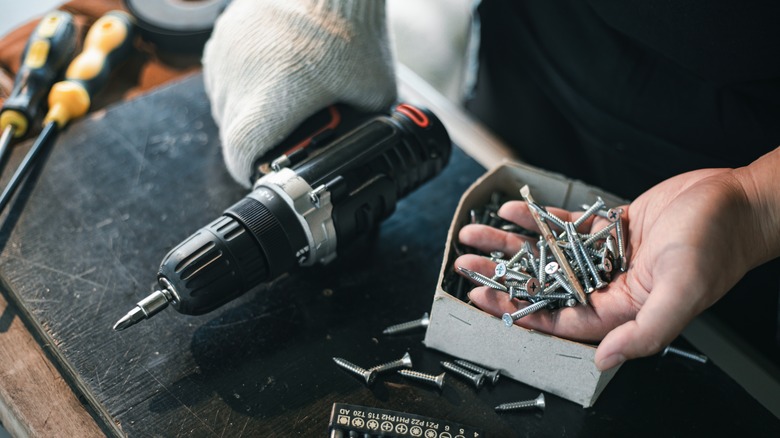 Hands holding drill and screws