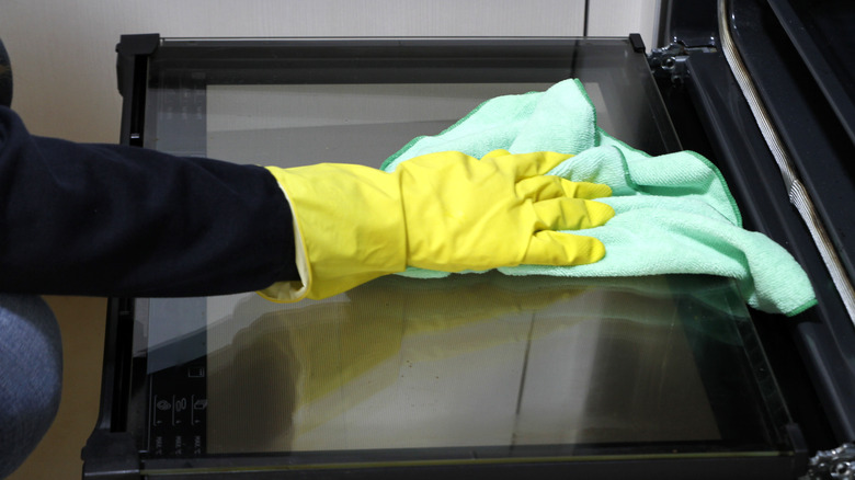 Gloved hand cleaning oven