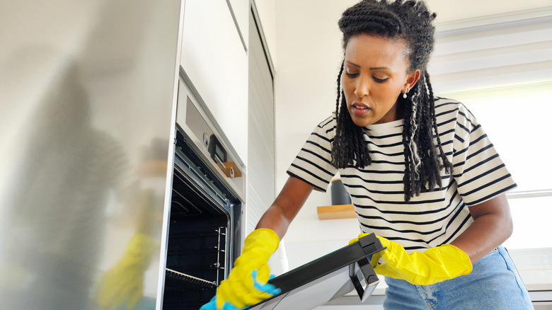 Woman wearing gloves cleaning oven 