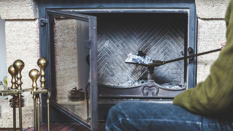 Person scooping out fireplace ash