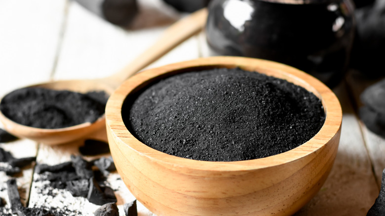 Close up of activated charcoal granules in wooden bowl.