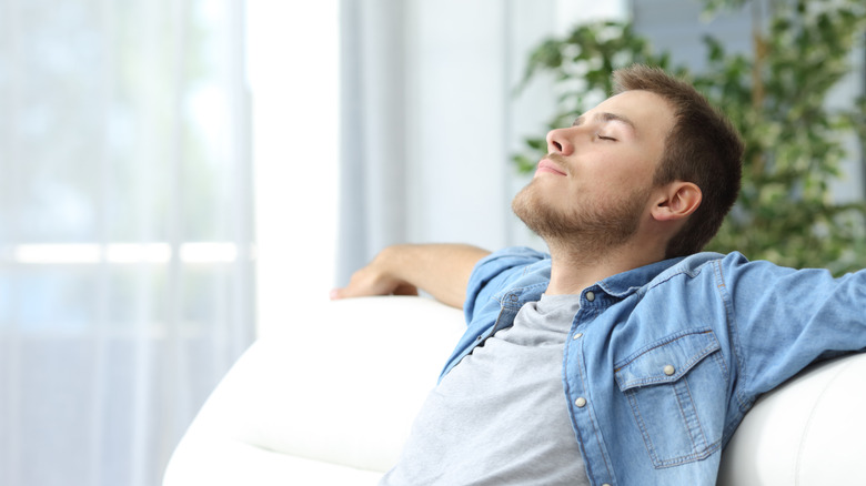 Person taking deep breath sitting on the couch.