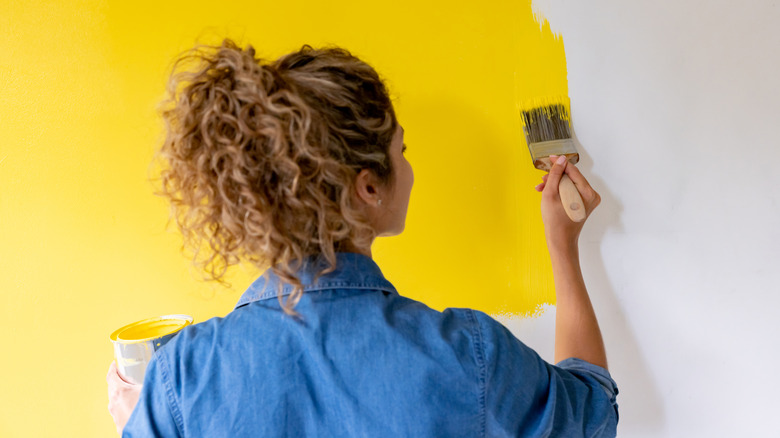 woman painting wall yellow