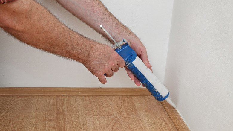 Person sealing corner of room