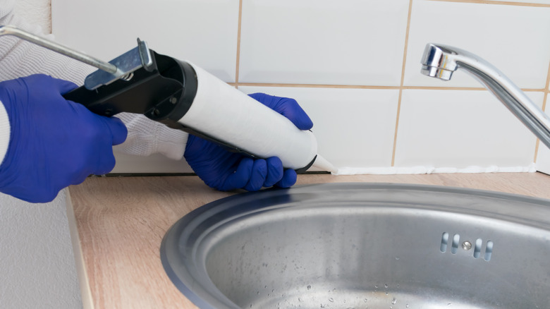 Person sealing sink with silicone