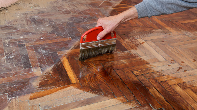 Hand spreading varnish on wood floor