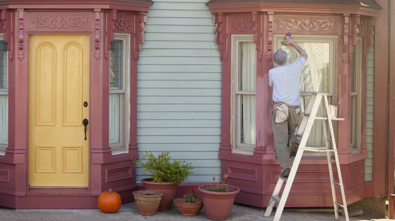 Man painting red home exterior