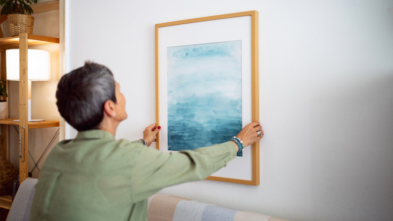 Woman decorating her home with a new painting