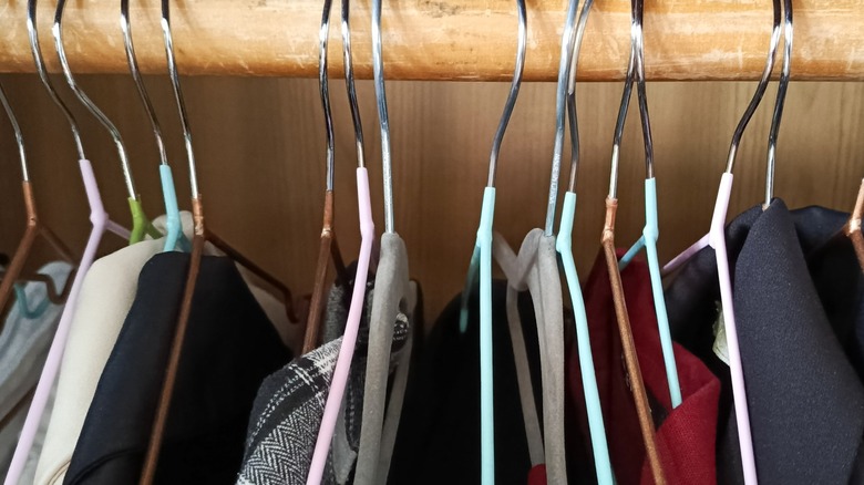 Clothes hang on wooden closet bar