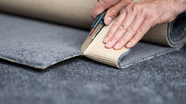 Person cutting carpet with blade