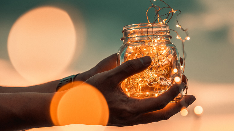 Man's hand holding jar with lights